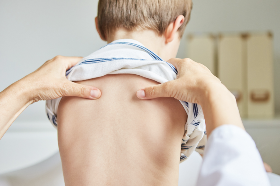 Chiropractor gently examining a child's back
